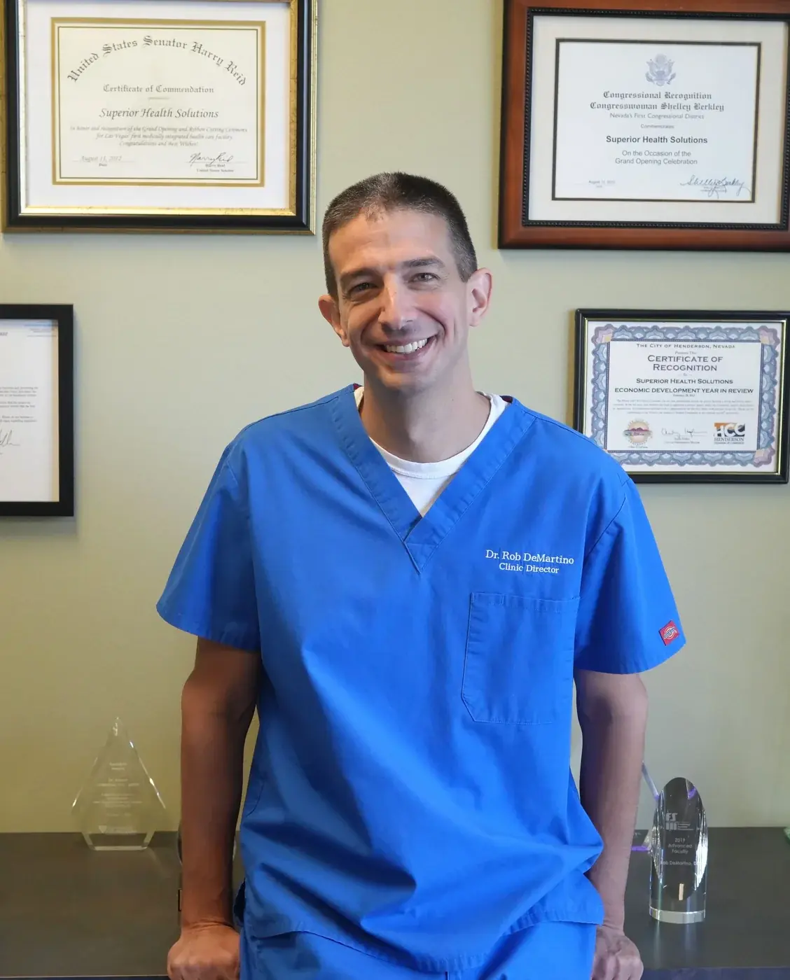 Dr. Rob DeMartino, DC standing in blue scrubs
